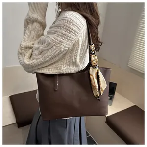 Detail of dark brown tote bag featuring white stitching and decorative silk scarf handle