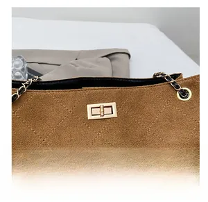 Gros plan du sac en daim marron avec surpiqûres en losanges et fermoir doré rotatif