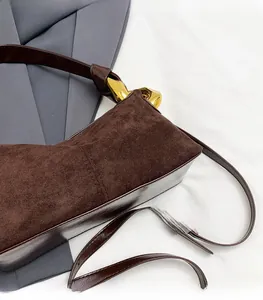 Detail of dark brown suede bag showing smooth texture and stylish golden metal hardware