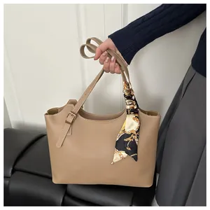 Close-up of khaki leather tote bag featuring a decorative silk scarf on the handle