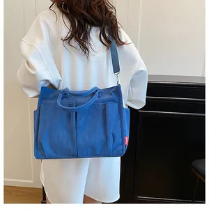 Dettaglio della borsa tote in velluto a coste blu con tasche frontali e logo Fashion rosso