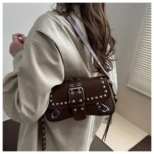Brown vintage shoulder bag with silver studs and buckle strap worn by a model
