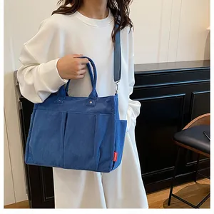 Dettaglio della borsa tote in velluto a coste blu con tasche e etichetta rossa