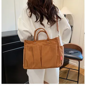 Dettaglio della borsa tote in velluto marrone con tasche frontali ed etichetta moda laterale