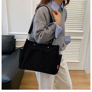Dettaglio della borsa tote in velluto a coste nero con tasche e etichetta FASHION