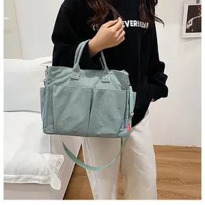 Dettaglio della borsa tote in velluto a coste verde chiaro con tasche e tracolla regolabile