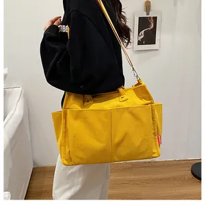 Dettaglio della borsa tote in velluto a coste giallo con tasche frontali ed etichetta