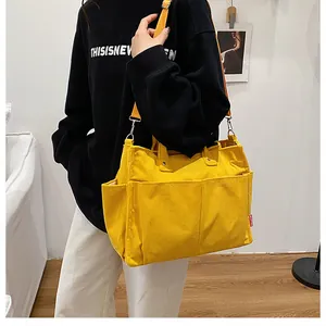 Dettaglio della borsa tote in velluto a coste giallo con tasche frontali e logo