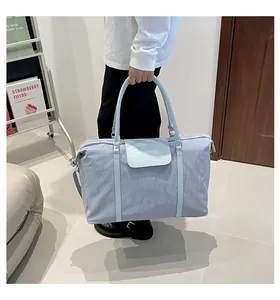 Close-up of light blue travel tote featuring textured nylon and premium metal hardware
