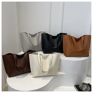 Detalle de bolsos tote minimalistas en cinco colores sobre una base blanca escalonada