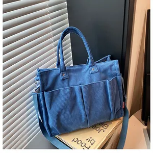 Dettaglio della borsa tote in velluto a coste blu scuro con tre tasche anteriori