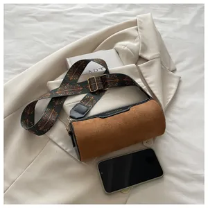 Detail der zylindrischen Tasche aus Wildleder mit gemustertem Gurt und Goldbeschlägen