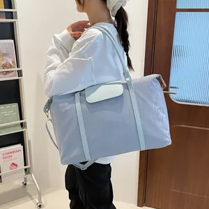 Large light blue travel bag with adjustable strap shown in a modern home setting