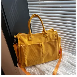Dettaglio della borsa tote in velluto giallo con doppie tasche e tracolla arancione