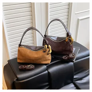 Detail of suede patchwork handbag featuring golden chain hardware and leather straps