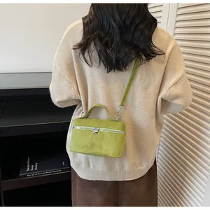 Sac boîte en daim vert porté par un mannequin avec détail de fermeture en cœur
