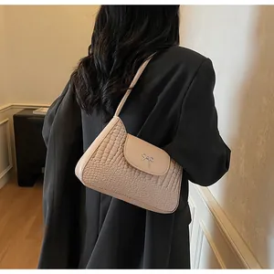 Détail du sac rose clair avec texture crocodile et boucle en forme de nœud argenté