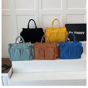 Dettaglio di cinque borse tote in velluto a coste in nero, giallo, verde, marrone e blu