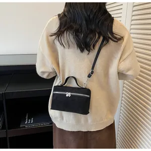 Detail of matte black crossbody bag featuring heart-shaped zippers and a top handle