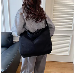 Vista lateral del bolso tote grande de pana negra con rayas verticales y estilo informal