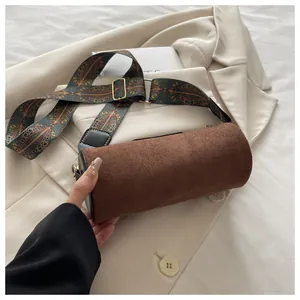 Detail einer dunkelbraunen Zylindertasche aus Wildleder mit bunt gewebtem Schultergurt
