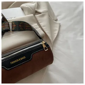 Detail der Zylindertasche aus braunem Wildleder mit buntem Tragegurt und Leder