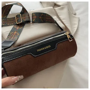 Nahaufnahme der braunen Zylindertasche mit besticktem Gurt und goldenen Metallbeschlägen
