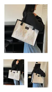 Close-up of beige tote bag with colorful embroidery and black brand logo label