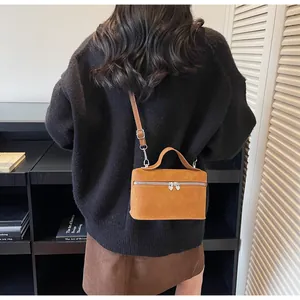 Detailed view of caramel box bag with heart-shaped metal zippers and top handle