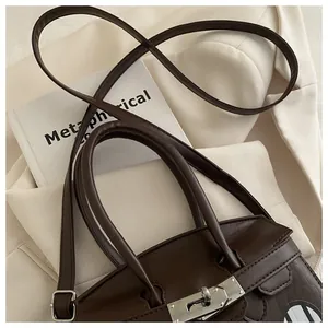 Detailed view of dark brown faux-crocodile leather handbag with silver lock and print