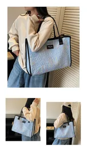 Detail of light blue quilted tote bag with colorful embroidery and black leather trim