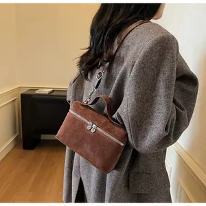 Detail of suede box bag featuring heart-shaped silver zipper and adjustable strap