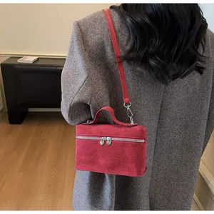 Detail of red suede vanity box bag featuring heart zipper and crossbody strap