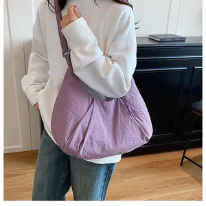Close-up of purple dumpling bag with textured nylon fabric and adjustable strap details
