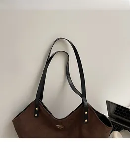 Detail of the soft shoulder straps and golden rivets on the dark brown suede tote bag