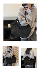 Close-up of black matte tote bag featuring a gold buckle and durable shoulder straps
