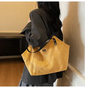 Detail view of mustard yellow quilted suede tote bag with metal twist lock and black straps