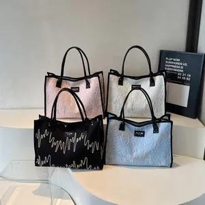 Sacs cabas matelassés avec broderie en quatre couleurs présentés sur un socle blanc