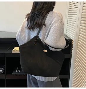 Detailed view of the large black tote bag featuring a gold rectangular metal turn-lock
