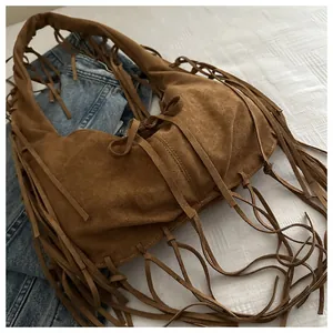 Détail d'un sac à bandoulière en daim marron avec de longues franges et nœud décoratif