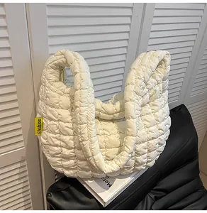 Détail du sac matelassé blanc montrant la texture douce et l'étiquette mode jaune