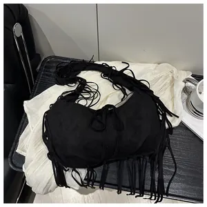 Détail du sac hobo en daim noir avec de longues franges et une forme en croissant minimaliste