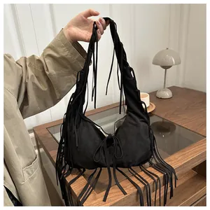 Détail du sac à bandoulière en daim noir montrant la texture des franges et le style hobo