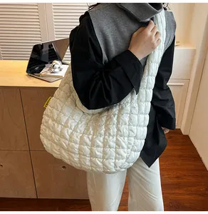 Détail du sac cabas matelassé blanc avec large bandoulière et étiquette de mode stylée