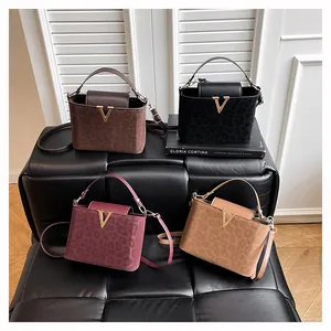 Détail de quatre sacs gaufrés léopard en marron, noir, bordeaux et beige avec boucle en V