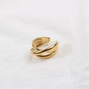 Bague multicouche en acier inoxydable doré tissé sur un fond de tissu texturé blanc