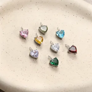 Eight colorful heart zircon pendants in silver frames on a textured ceramic plate