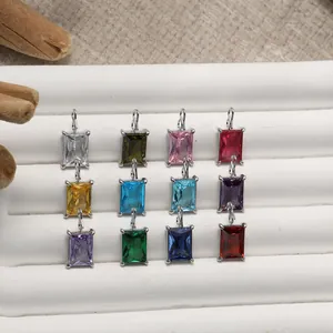 Twelve rectangular zircon charms in various colors with silver bails on a display stand