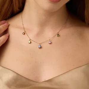 Close-up of a gold necklace with five multi-colored round zircon stones on a model