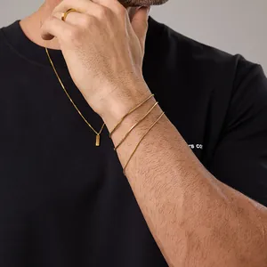 Primo piano di bracciali a catena serpente dorata e anello quadrato per uomo
